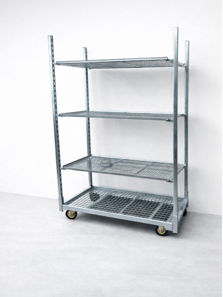 Metalen rek met vier planken en wielen, tegen een witte muur.